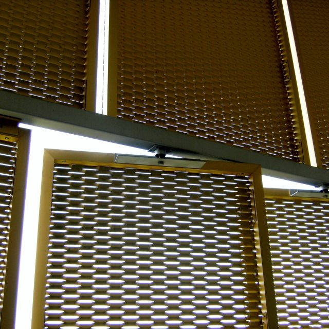 Rivestimento in rete stirata colore giallo oro: dettaglio apribili motorizzati.